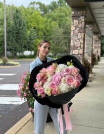 Elegant pastel flower bouquet with white and pink hydrangeas and garden roses wrapped in black.