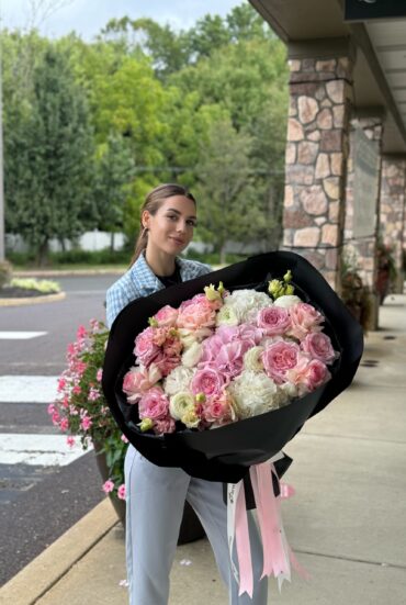 Elegant pastel flower bouquet with white and pink hydrangeas and garden roses wrapped in black.