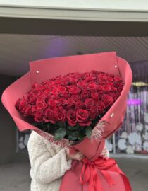 Extra-large bouquet of 101 premium red roses wrapped in elegant red paper with satin ribbons." "Luxurious arrangement of deep red roses, perfect for grand romantic gestures." "A person holding a stunning bouquet of 101 red roses in elegant wrapping."