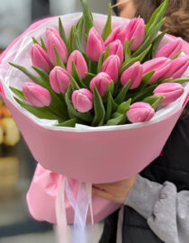 A vibrant bouquet of pink tulips with delicate petals and lush green leaves.