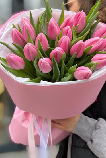 A vibrant bouquet of pink tulips with delicate petals and lush green leaves.