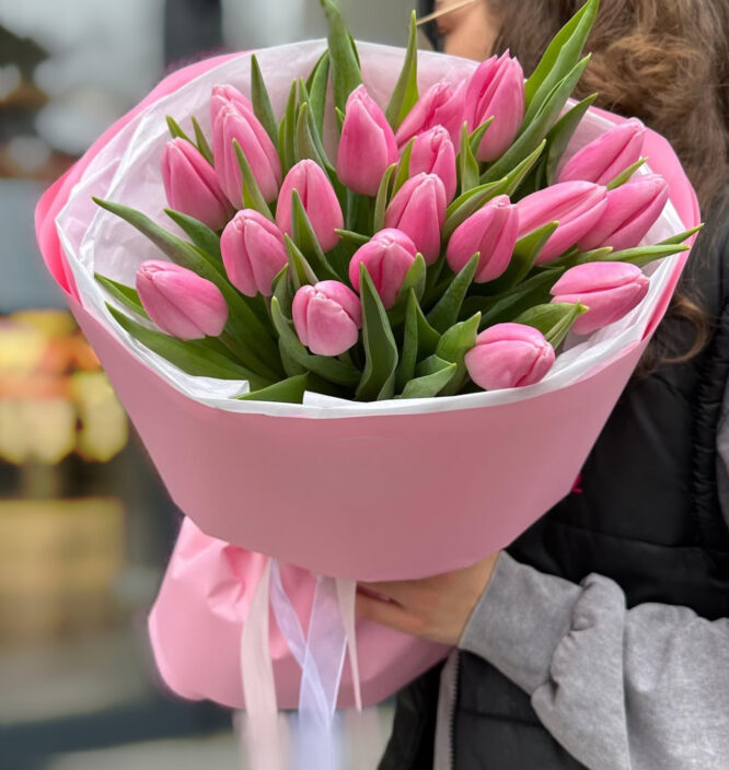 A vibrant bouquet of pink tulips with delicate petals and lush green leaves.