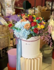 Elegant box arrangement featuring hydrangeas, tulips, and ranunculus in a harmonious floral display. Title: