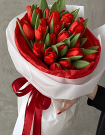 Elegant bouquet of red tulips with vibrant petals and lush green foliage.