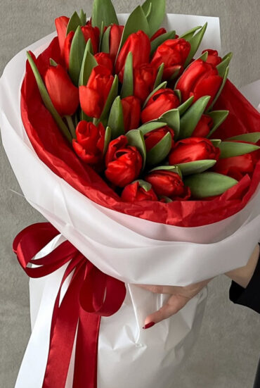 Elegant bouquet of red tulips with vibrant petals and lush green foliage.