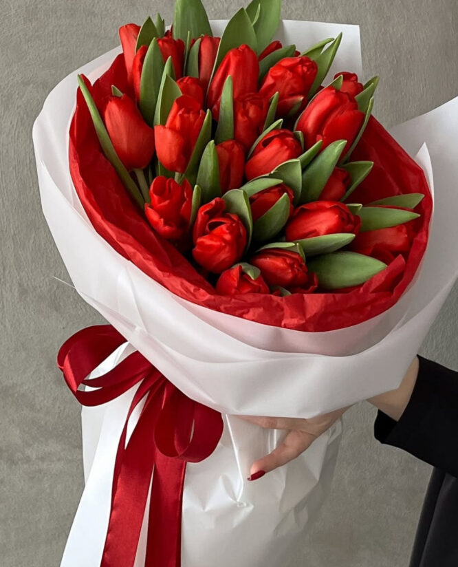 Elegant bouquet of red tulips with vibrant petals and lush green foliage.